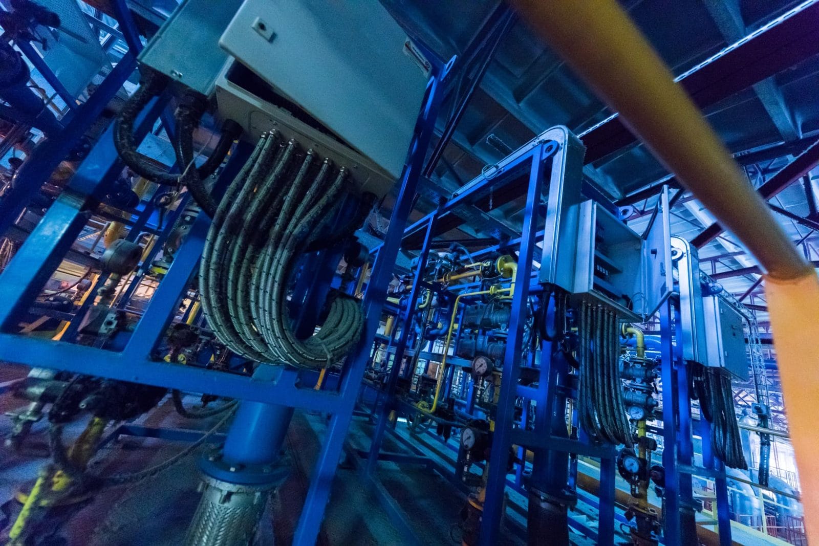 Blue-lit industrial low voltage infrastructure with conduit runs, control enclosures and cabling